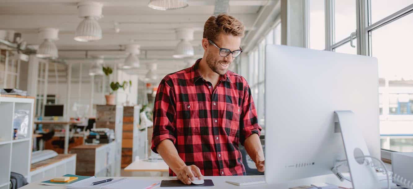 Creative professional standing at computer looking for creative jobs in Charlotte, NC